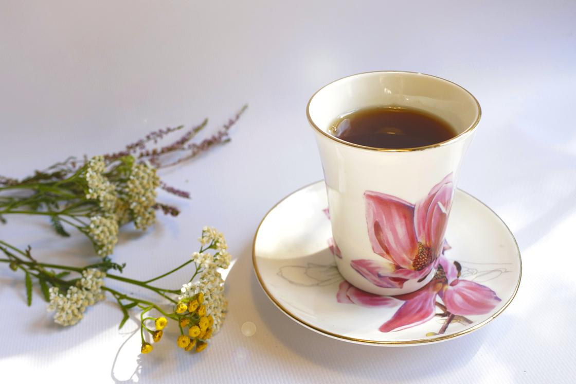 Черный чай в чашке и цветы