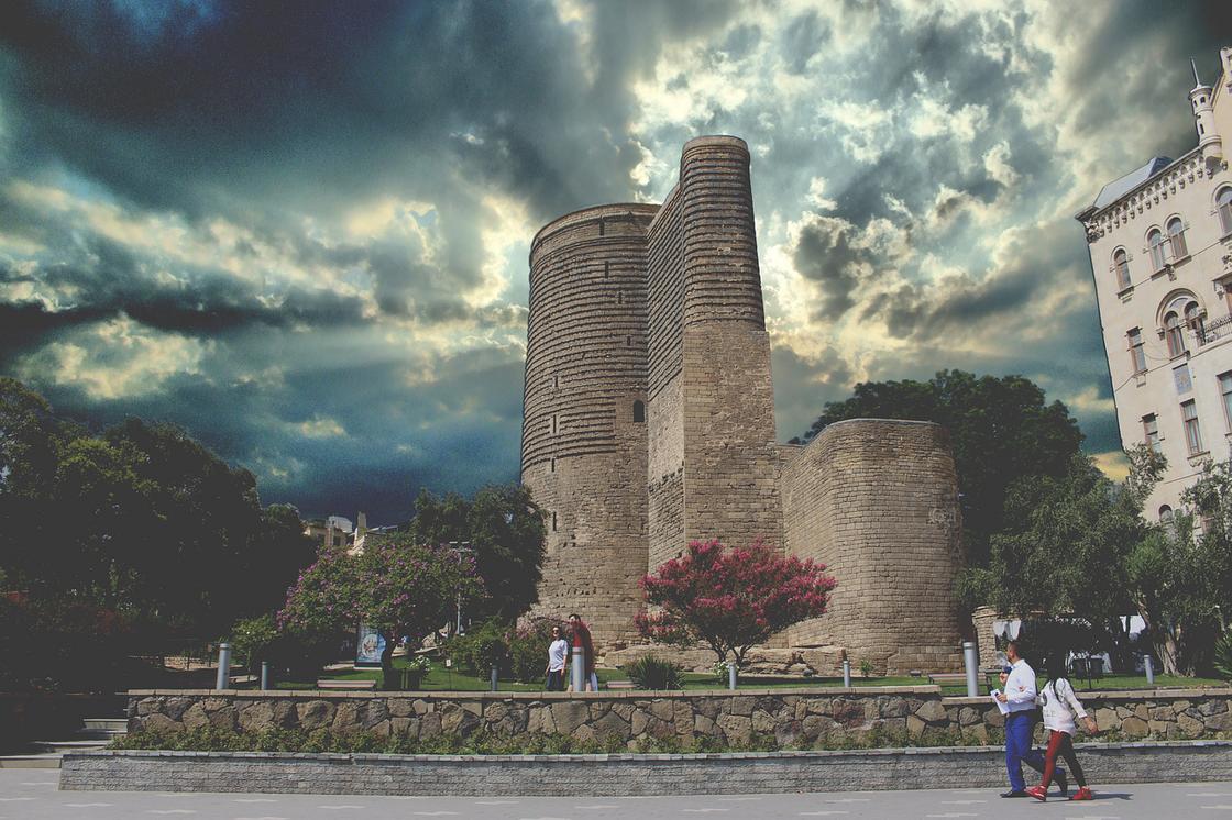 Вид на Девичью башню в Баку, мимо которой проходят люди
