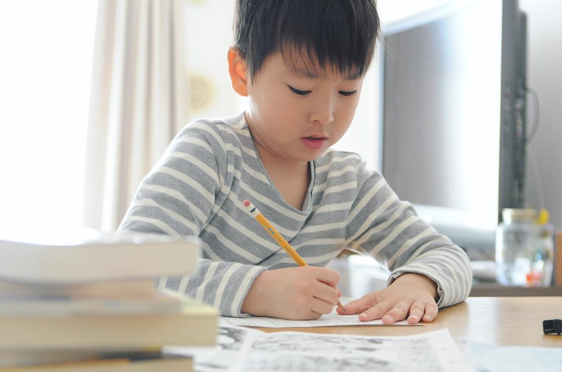 Мальчик за столом с простым карандашом в руке