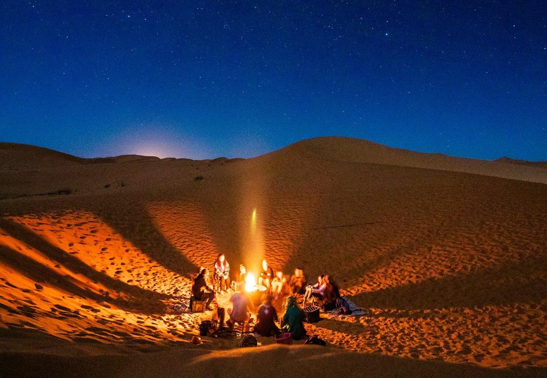 Люди сидят у костра в пустыне