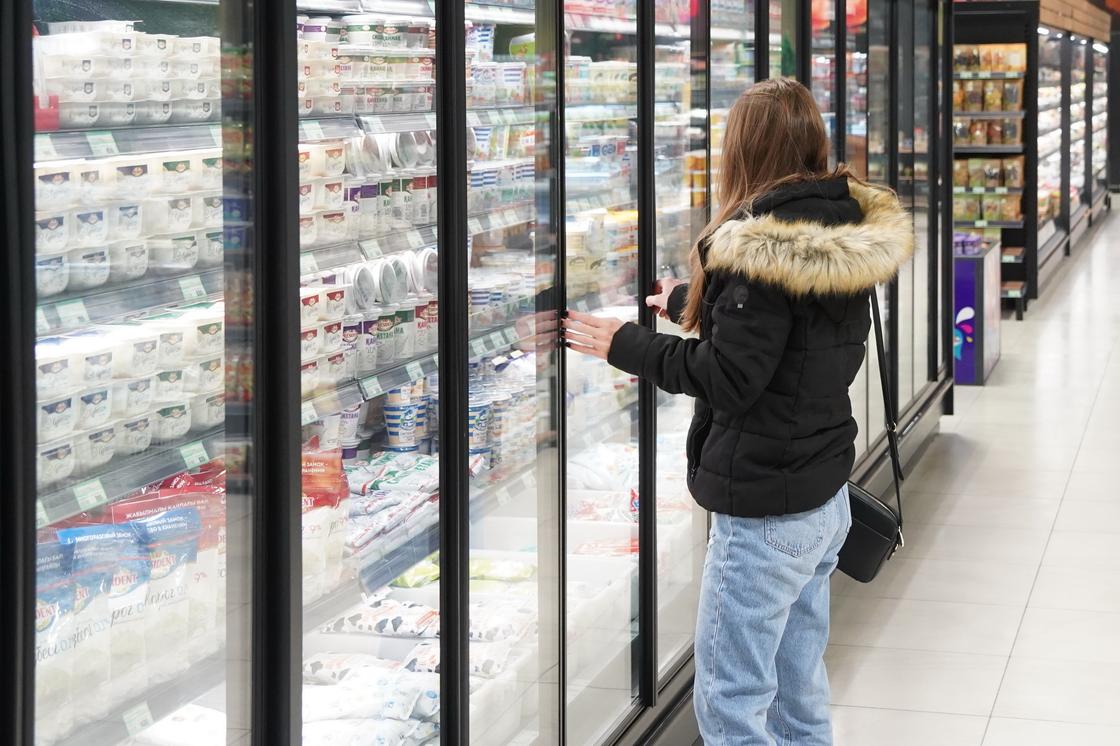 Девушка выбирает продукты в супермаркете.