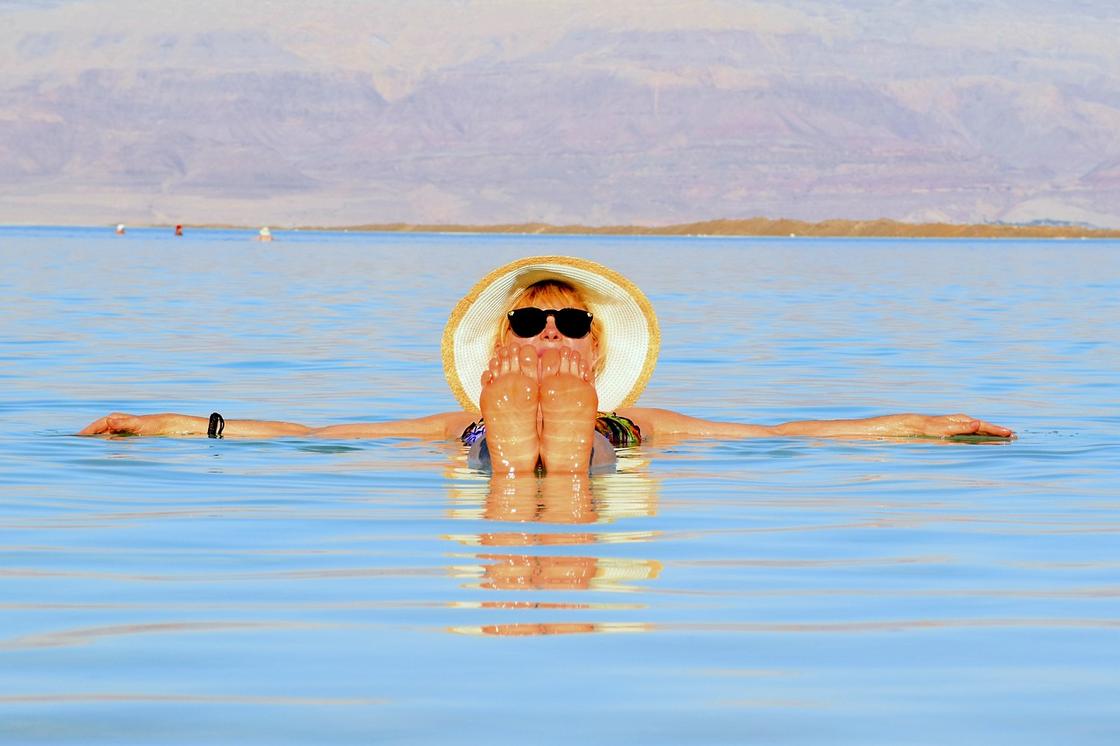 Девушка в шляпе на поверхности воды Мертвого моря