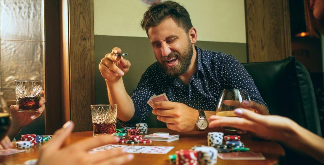 Мужчина пьет, курит и играет в карты