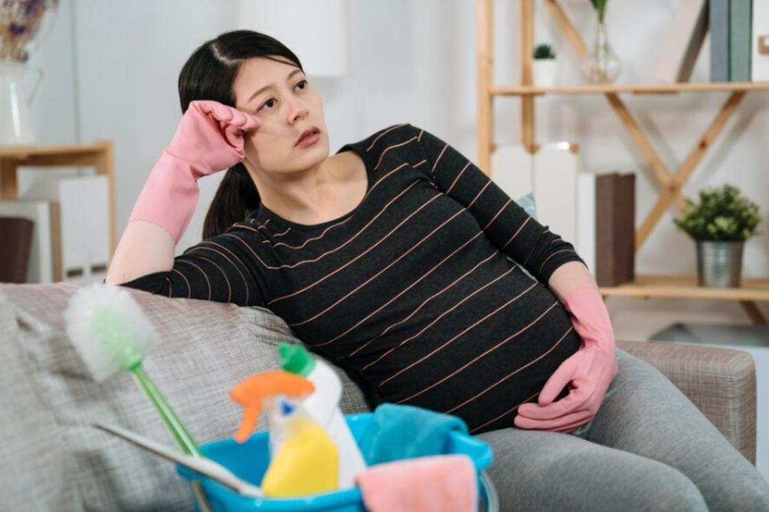 Беременная женщина отдыхает во время уборки дома