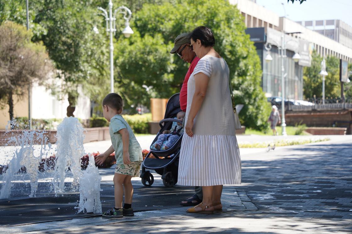 Женщина, мужчина и дети у фонтана в Алматы