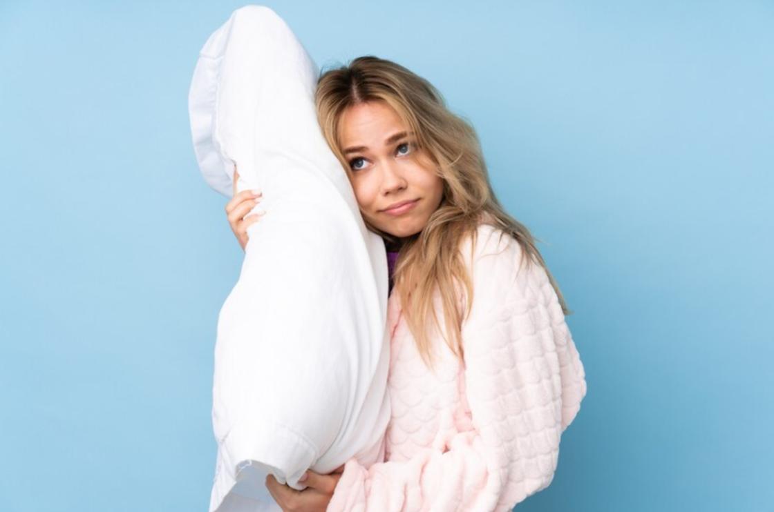 Девушка в халате держит в руках подушку