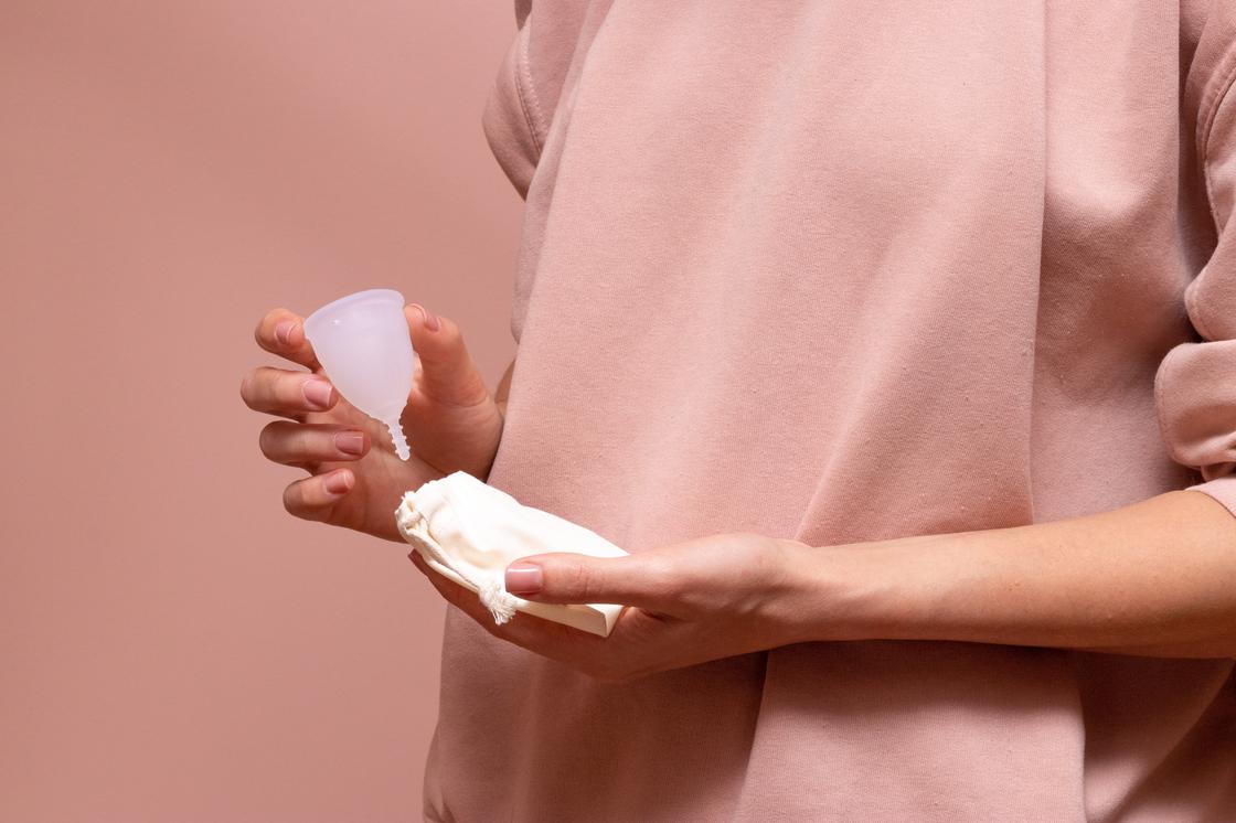 Девушка держит в руках менструальную чашу