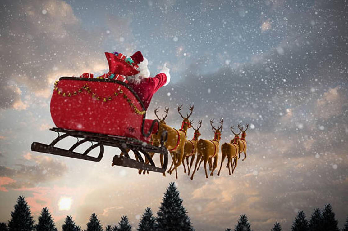 Санта-Клаус летит в санях по небу