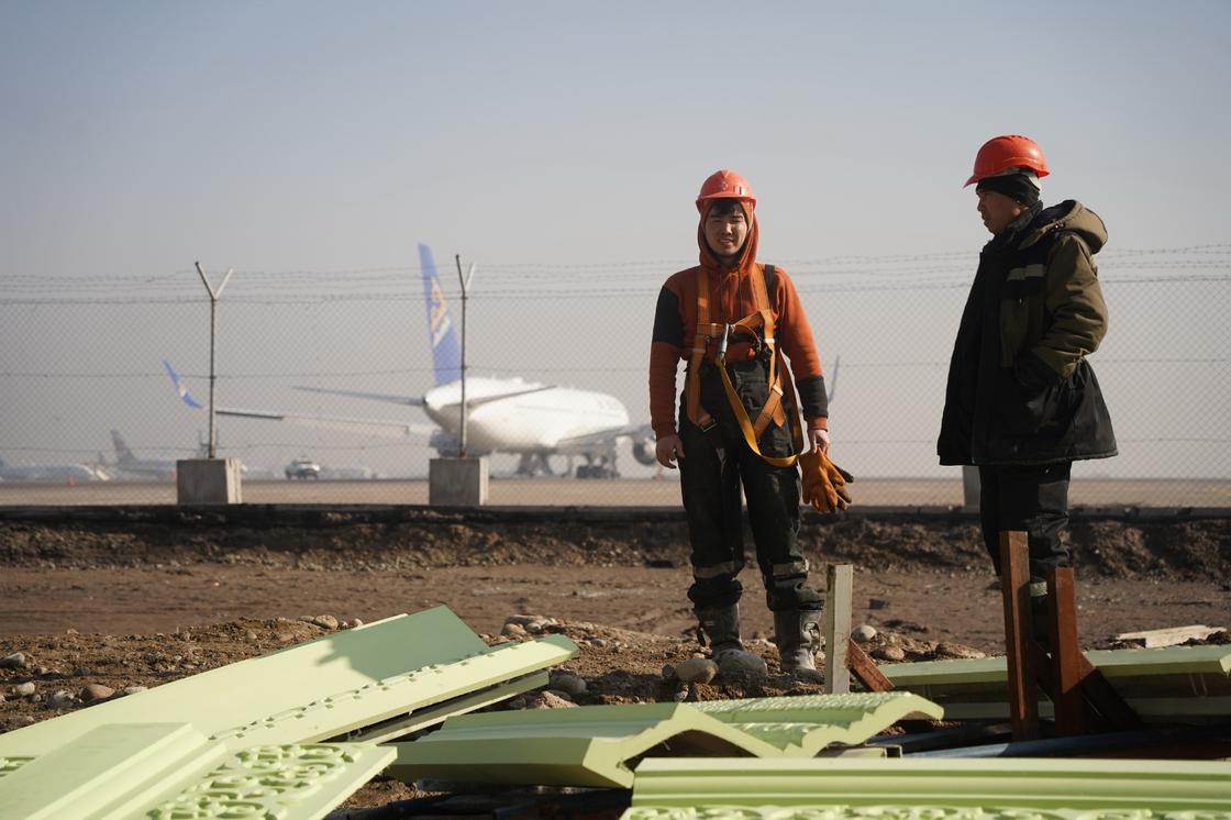 Строители стоят на фоне самолета