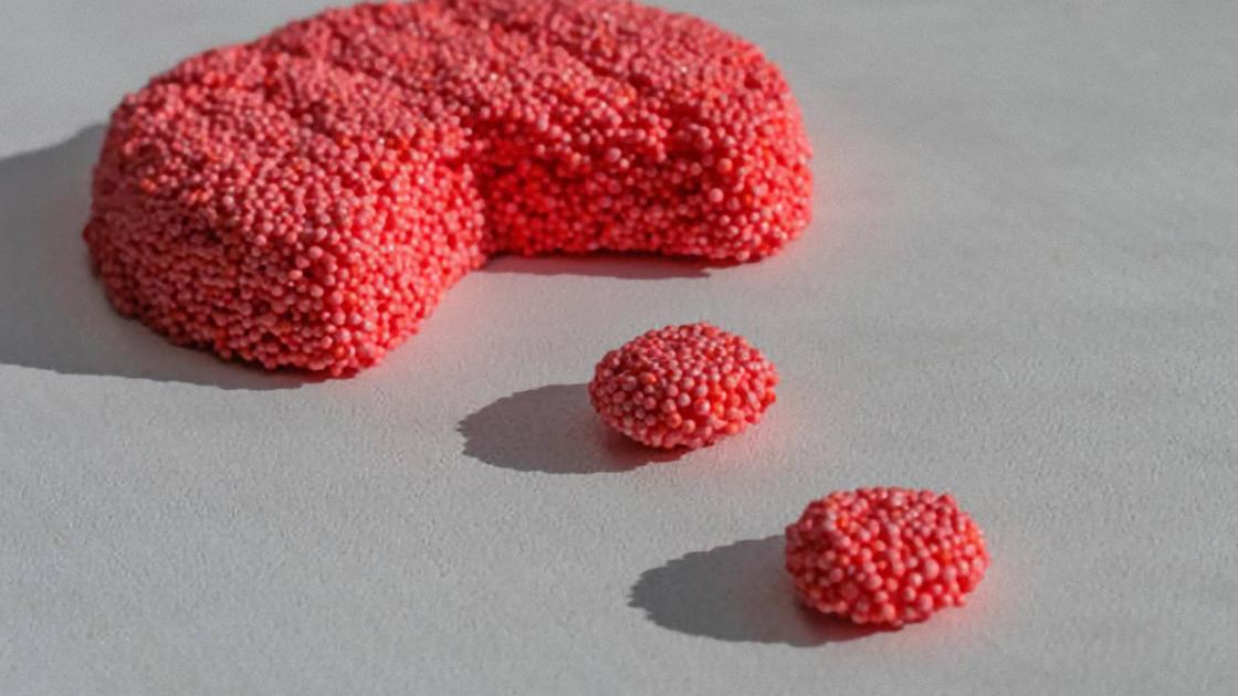 Большой кусок красного пластилина с шариками из пенопласта с вырезанным фрагментом. Два маленьких круглых кусочка
