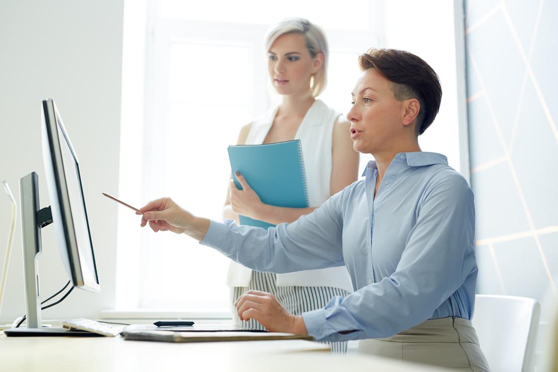 Женщина показывает информацию на экране компьютера коллеге