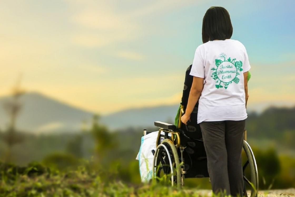 Женщина стоит рядом с женщиной в инвалидной коляске