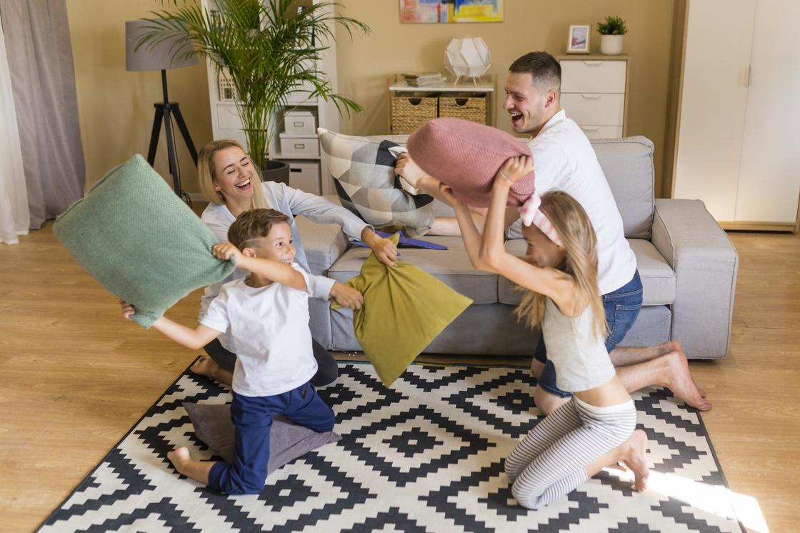 Родители и дети играют и бьются подушками