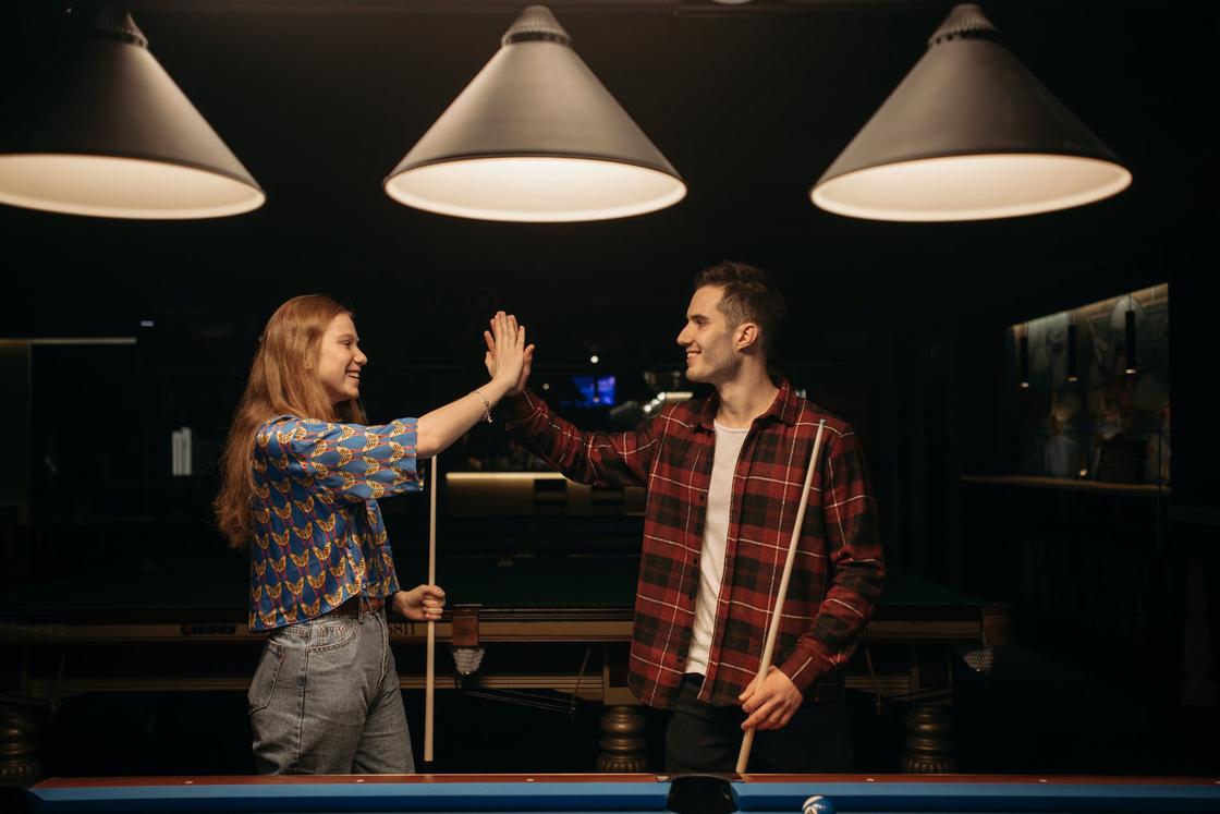 Chlap a dívka u kulečníkového stolu s tága v rukou