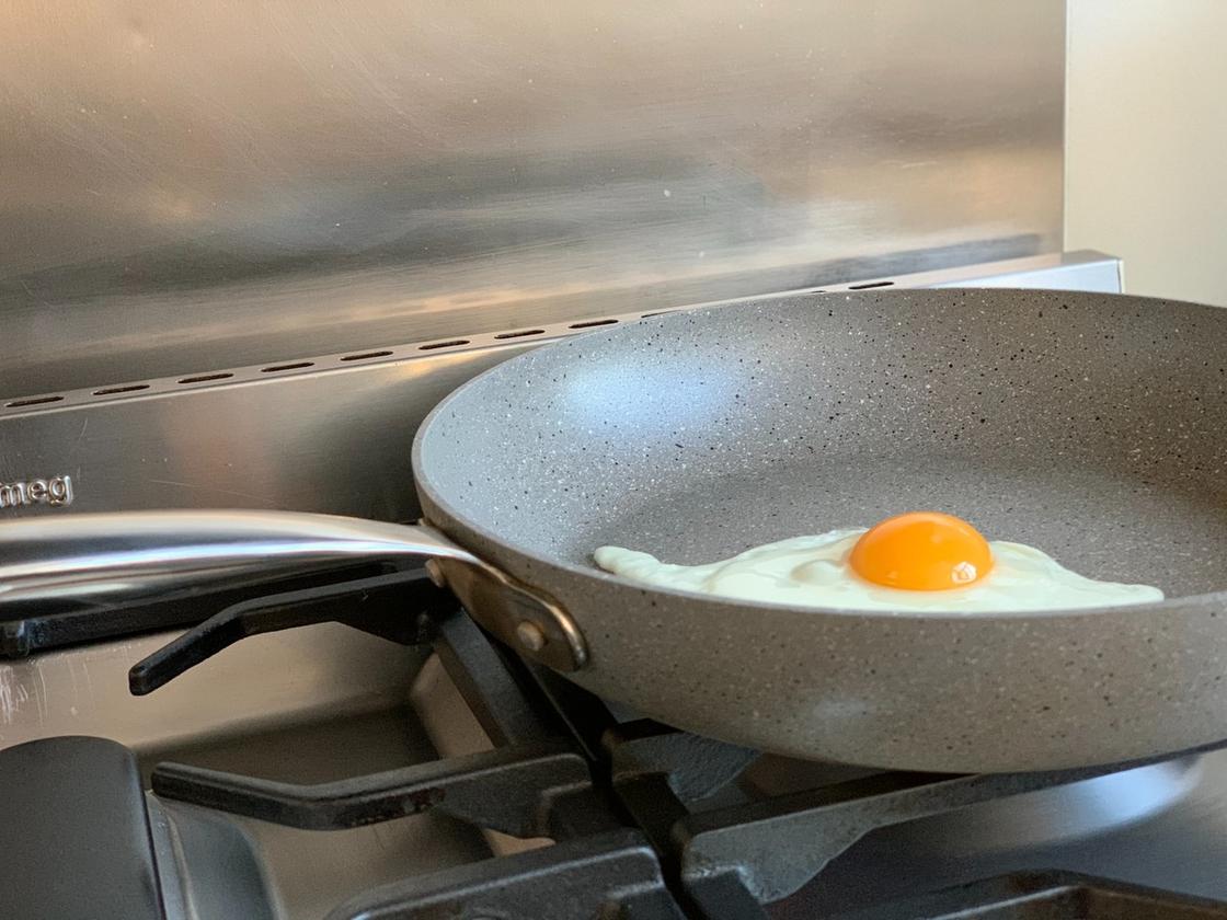 В сковороде на газовой плите жарится яичница