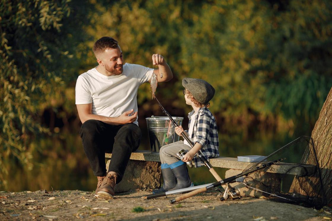 Мужчина и мальчик на берегу реки со снастями