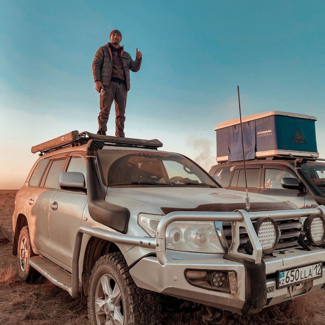 Роман Бугаев стоит на крыше автомобиля