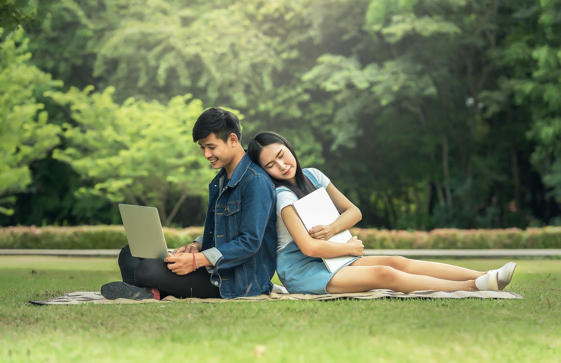 Парень и девушка сидят на поляне в парке