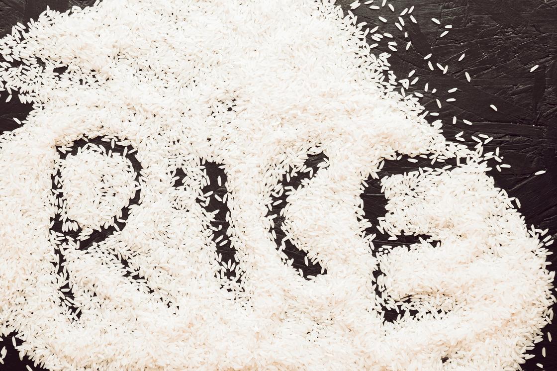 На столе рассыпан рис. Написано английское слово rice, которое переводится как рис