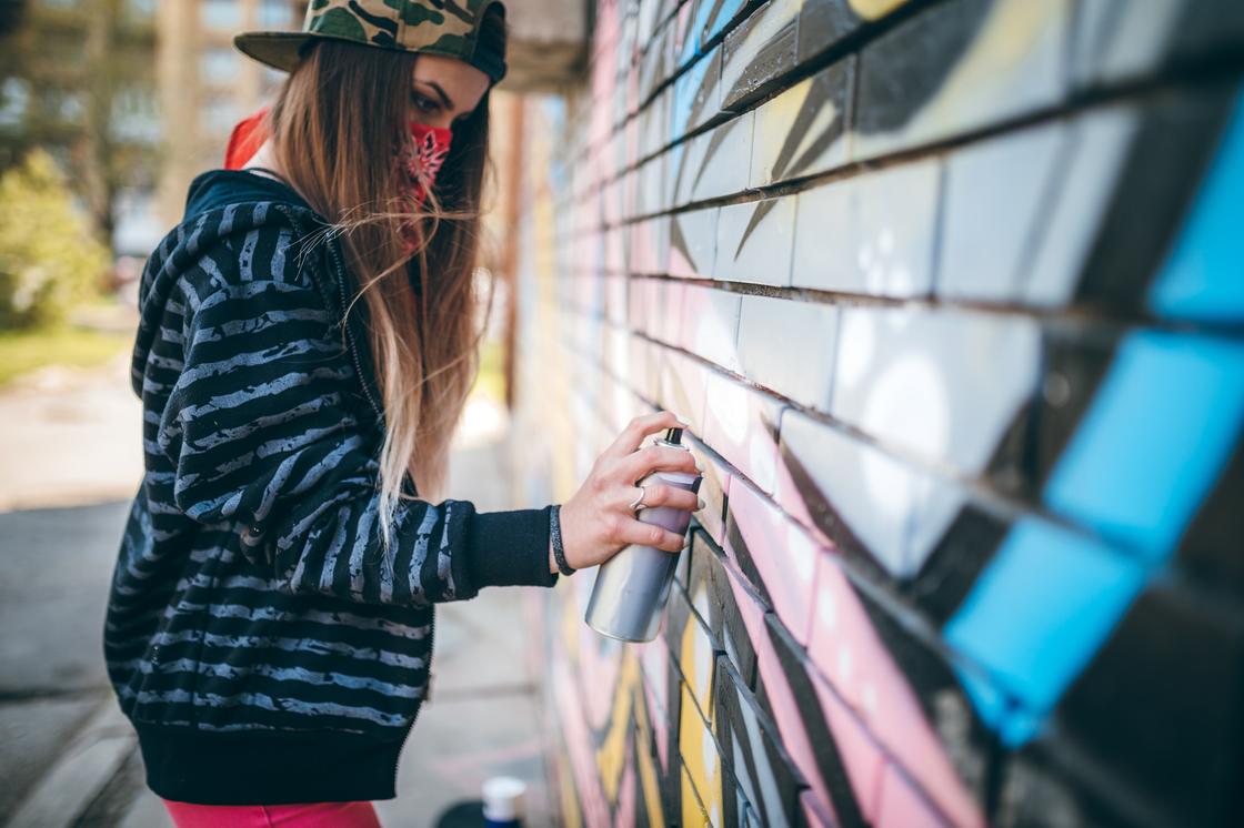 Девочка рисует на стене здания