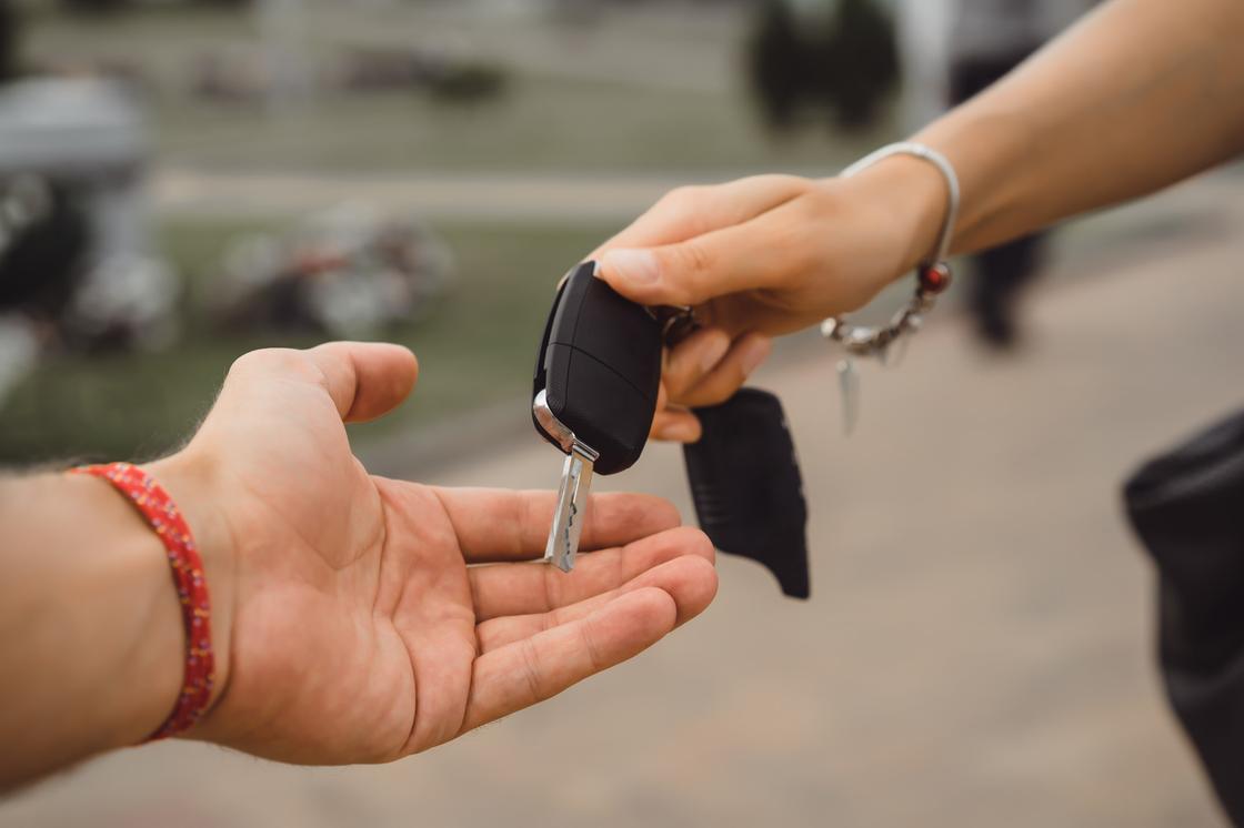 Женская рука вкладывает в мужскую ключи от автомобиля