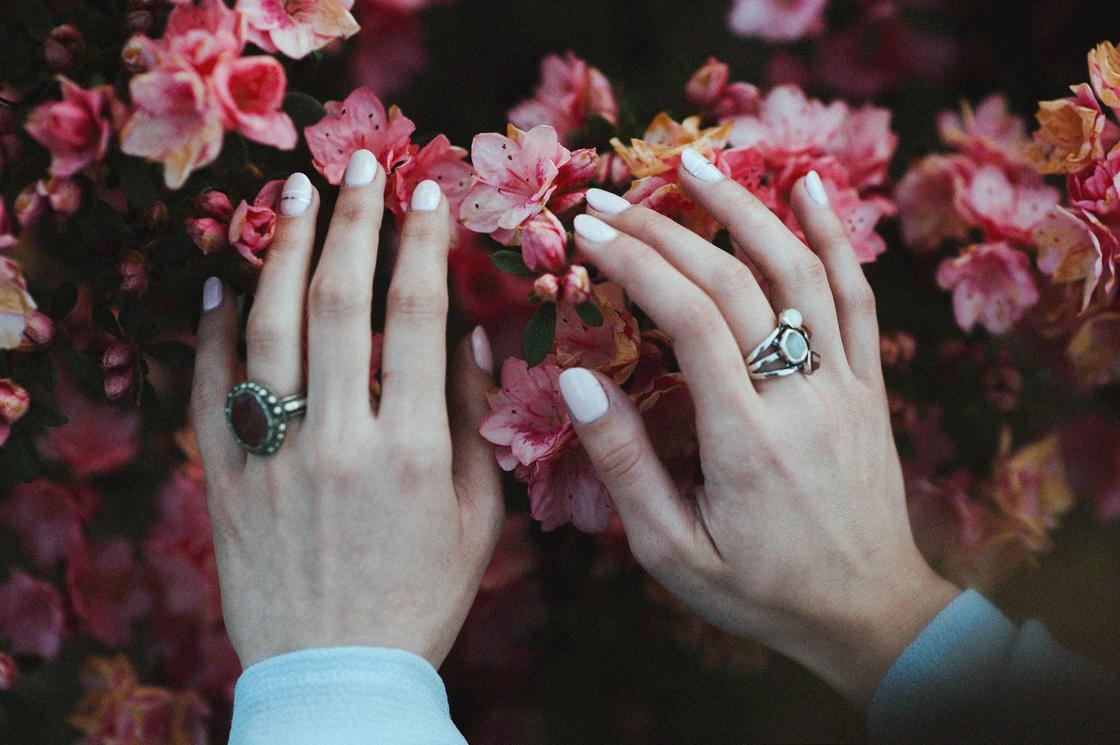 Женские руки на цветах в кольцах