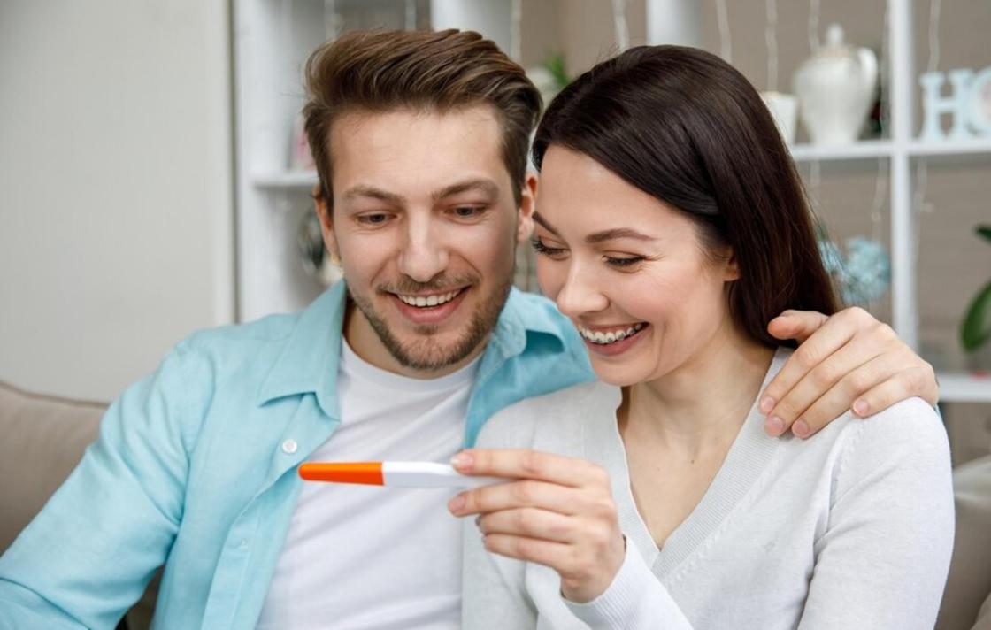 Счастливая пара с тестом на беременность в руках