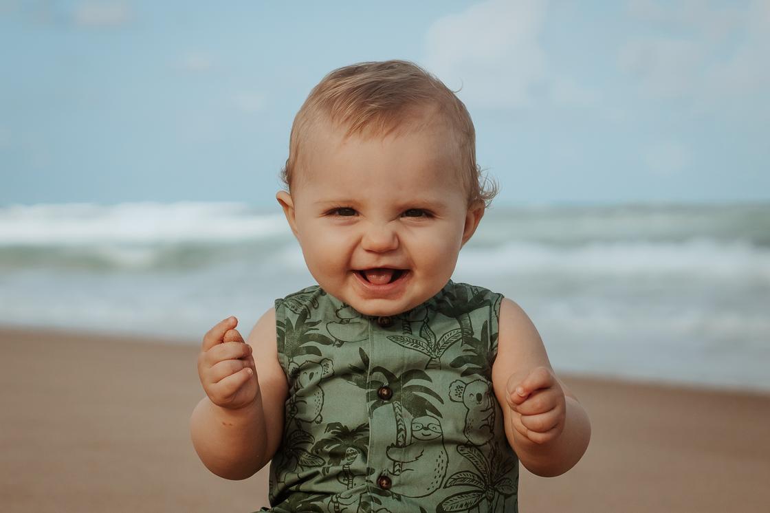 Ребенок стоит на фоне моря и улыбается