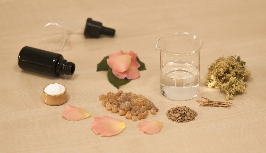 На столе основа для создания духов, аромамасло и растительные ингредиенты
