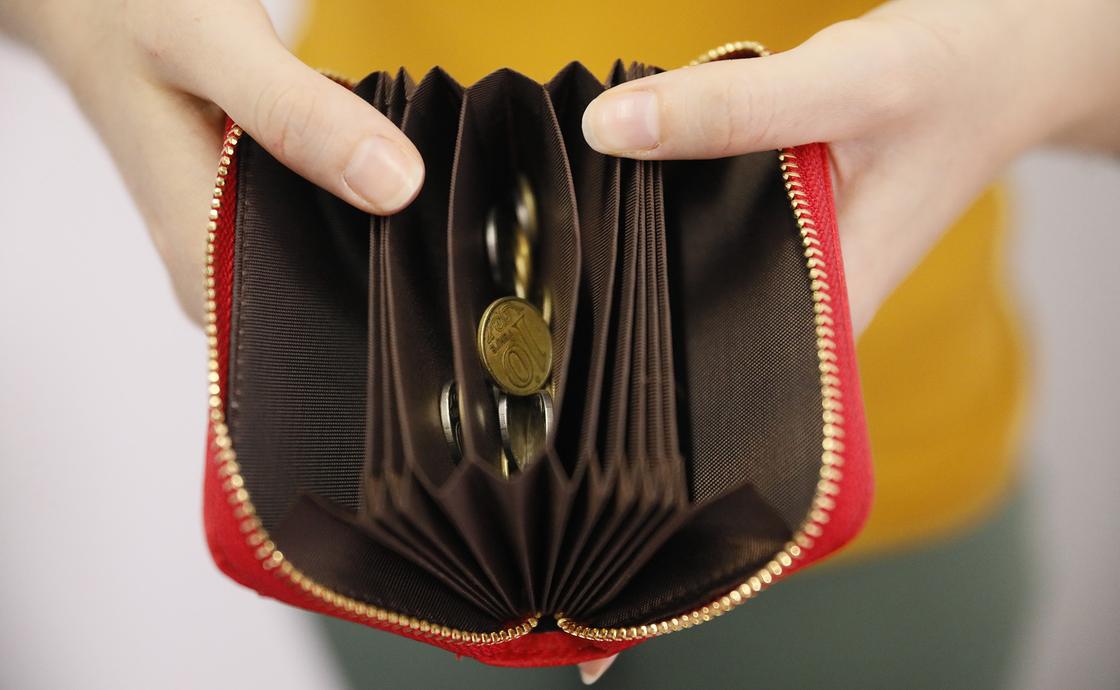 Женщина держит в руках кошелек с монетами