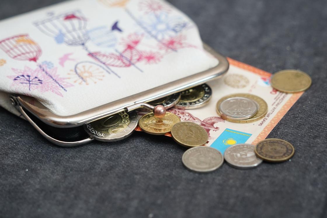 Кошелек с монетами и купюрами тенге лежит на столе