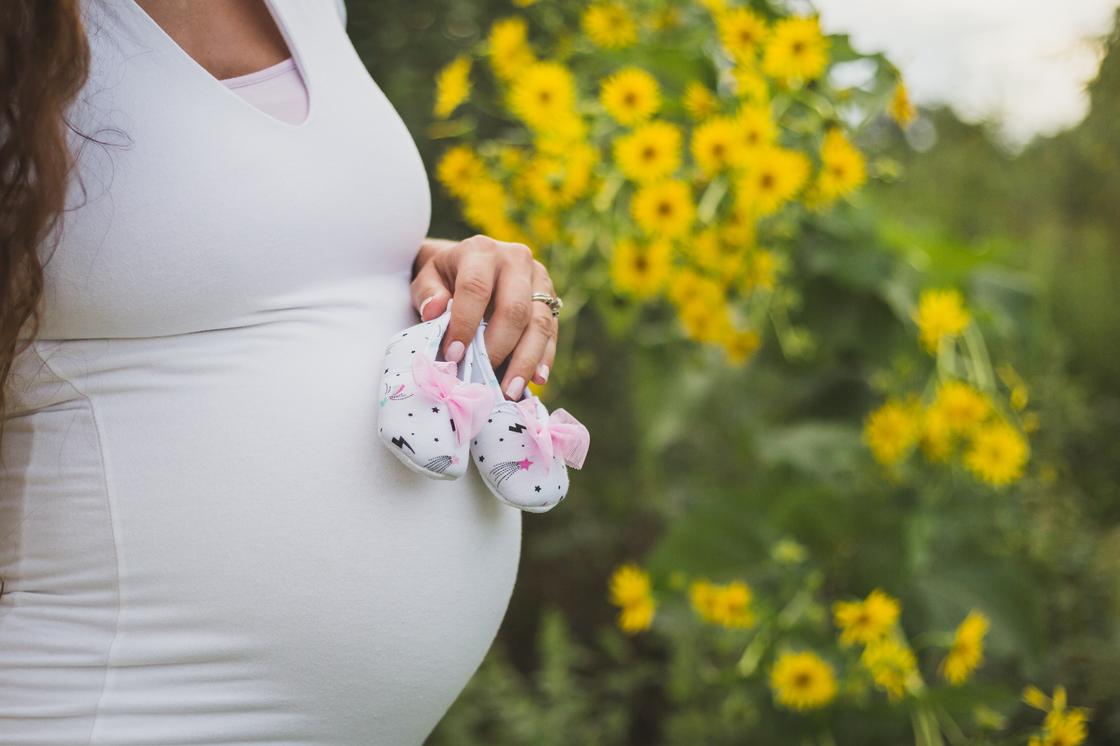 Беременная женщина на фоне цветов
