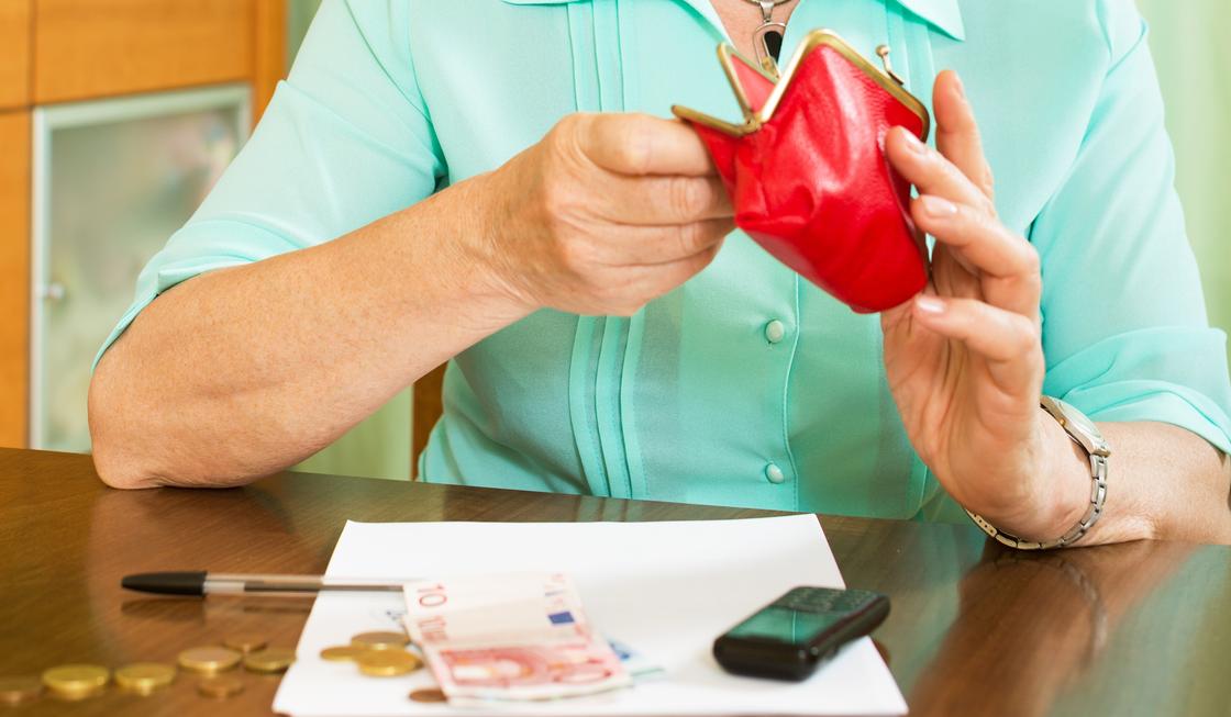 Пенсионерка заглядывает в свой кошелек