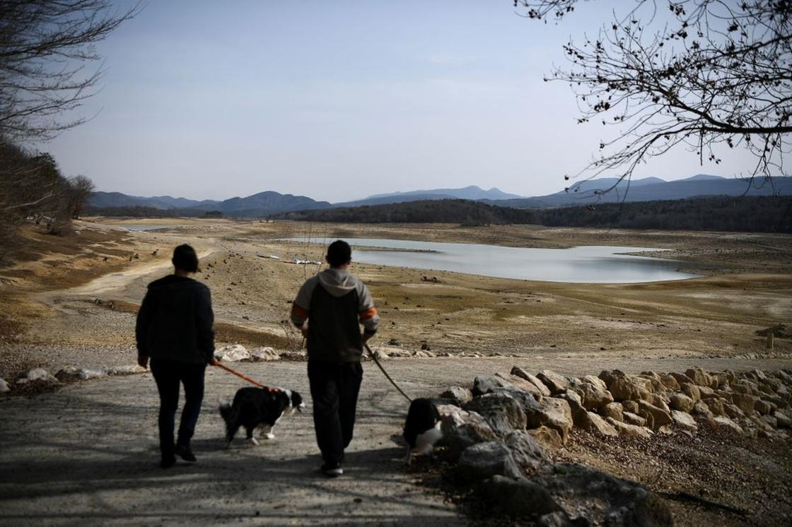 Люди выгуливают собак близ высыхающего озера Монбель (Франция), 21 февраля 2023 года