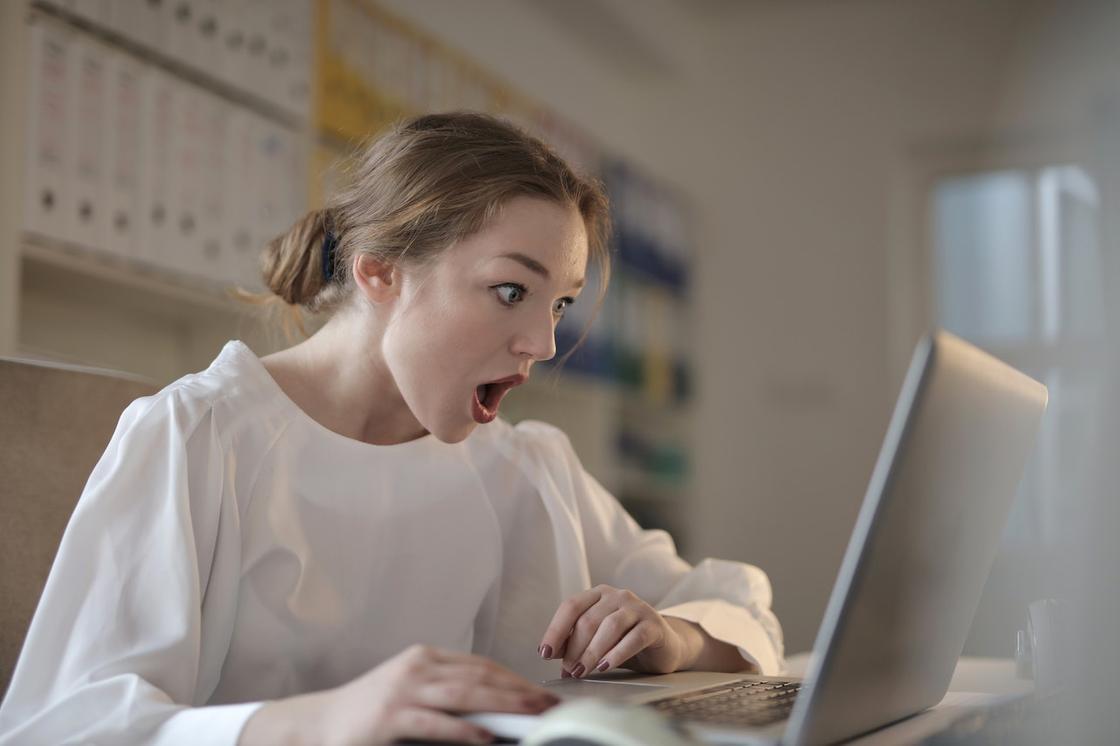 Девочка-подросток удивленно смотрит на экран ноутбука