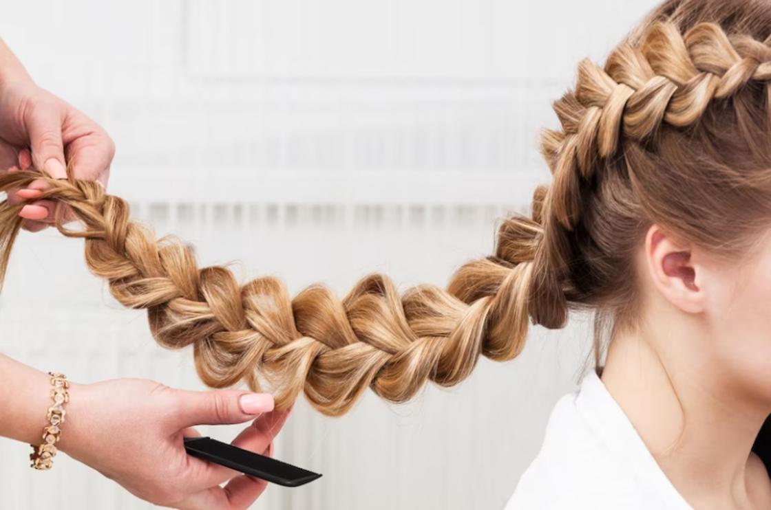 Девушке делают плетение на длинных волосах