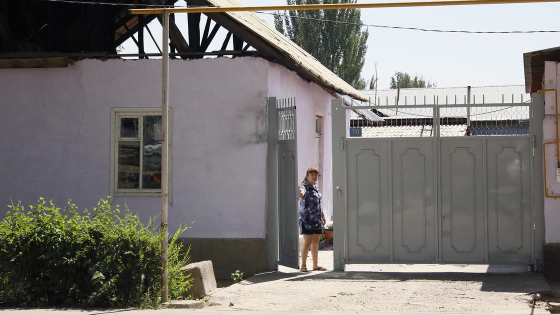 Девушка стоит возле ворот дома