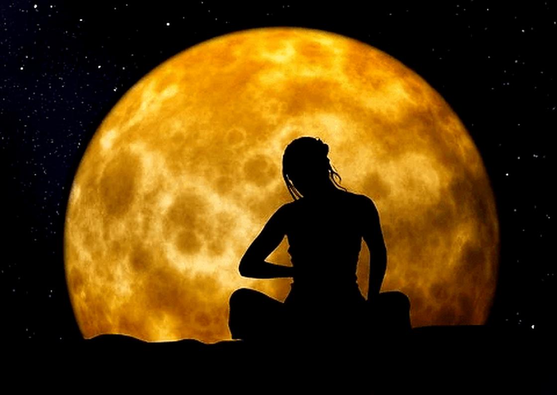 Женщина на фоне Луны занимается йогой