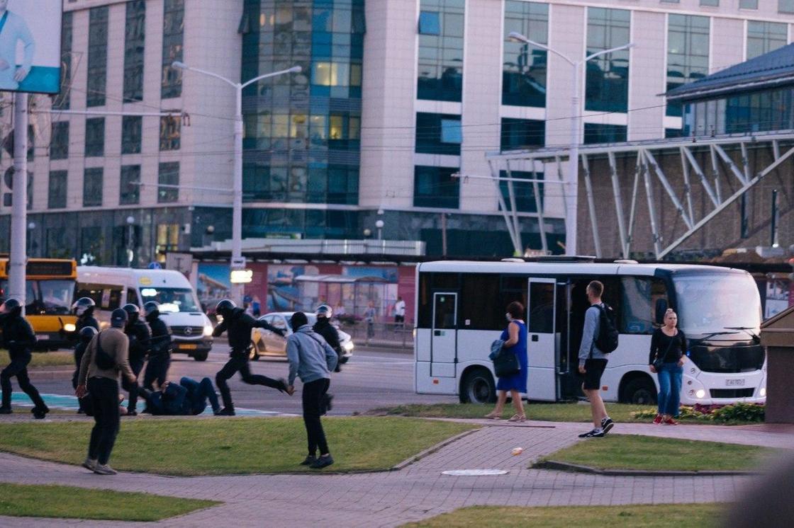 люди стоят рядом с автобусом и смотрят на избиение человека