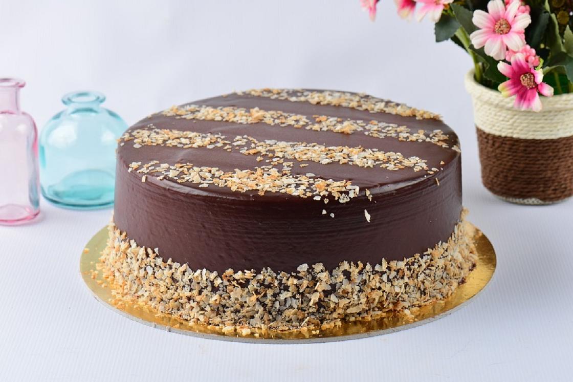 Шоколадный торт, покрытый глазурью и украшенный ореховой крошкой