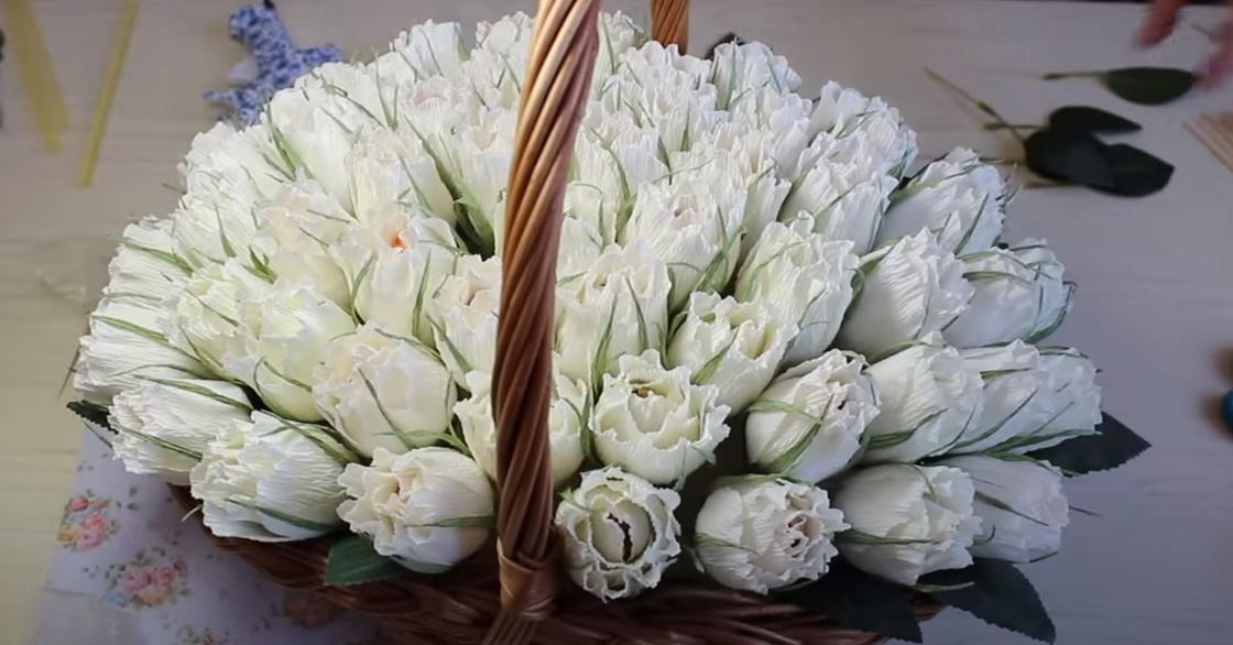 Букет белых полураскрытых роз в корзине. Цветы сделаны из гофрированной бумаги с конфетой внутри