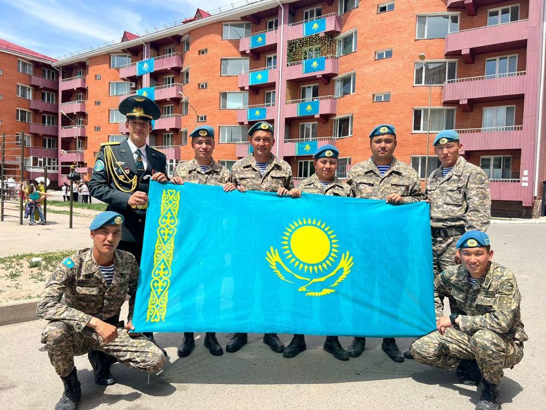 Казахстанские военнослужащие держат флаг Казахстана
