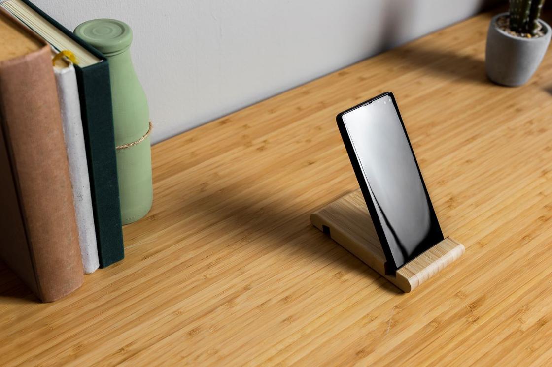 Книги и телефон на подставке на столе