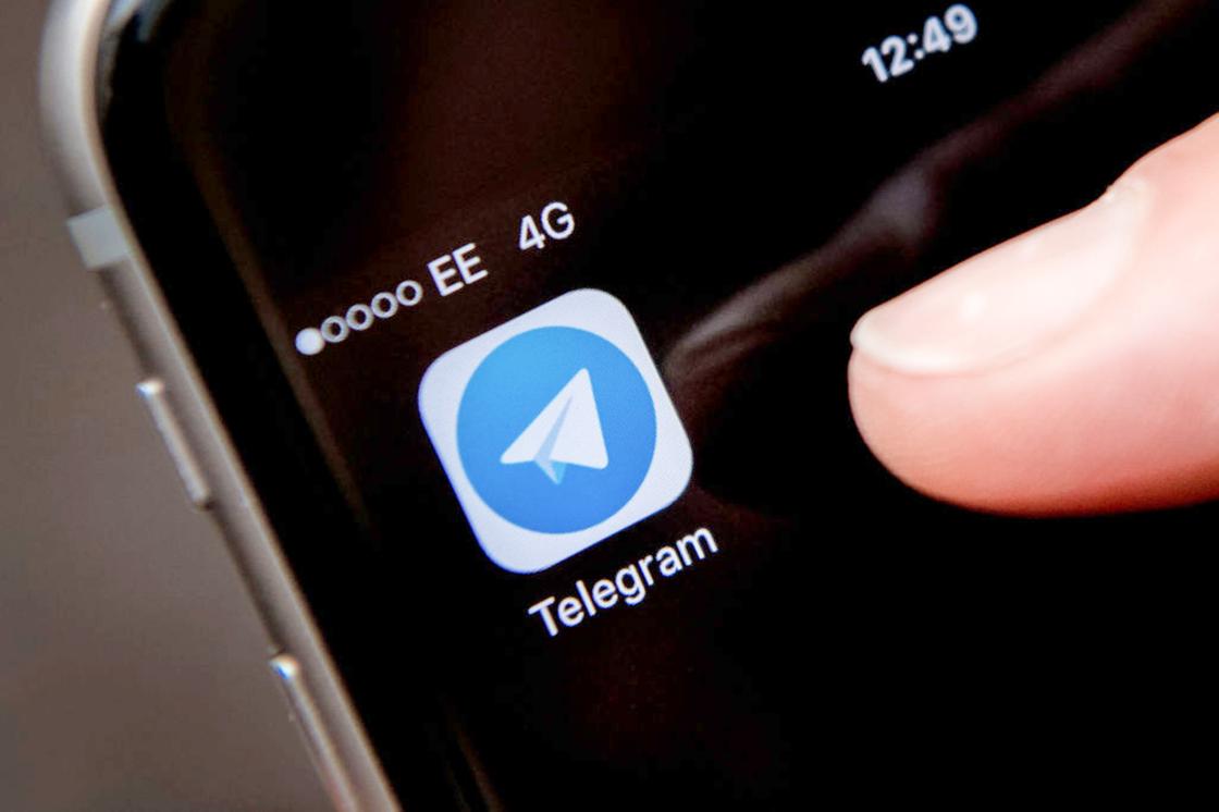 Человек нажимает пальцем руки на иконку приложения Telegram