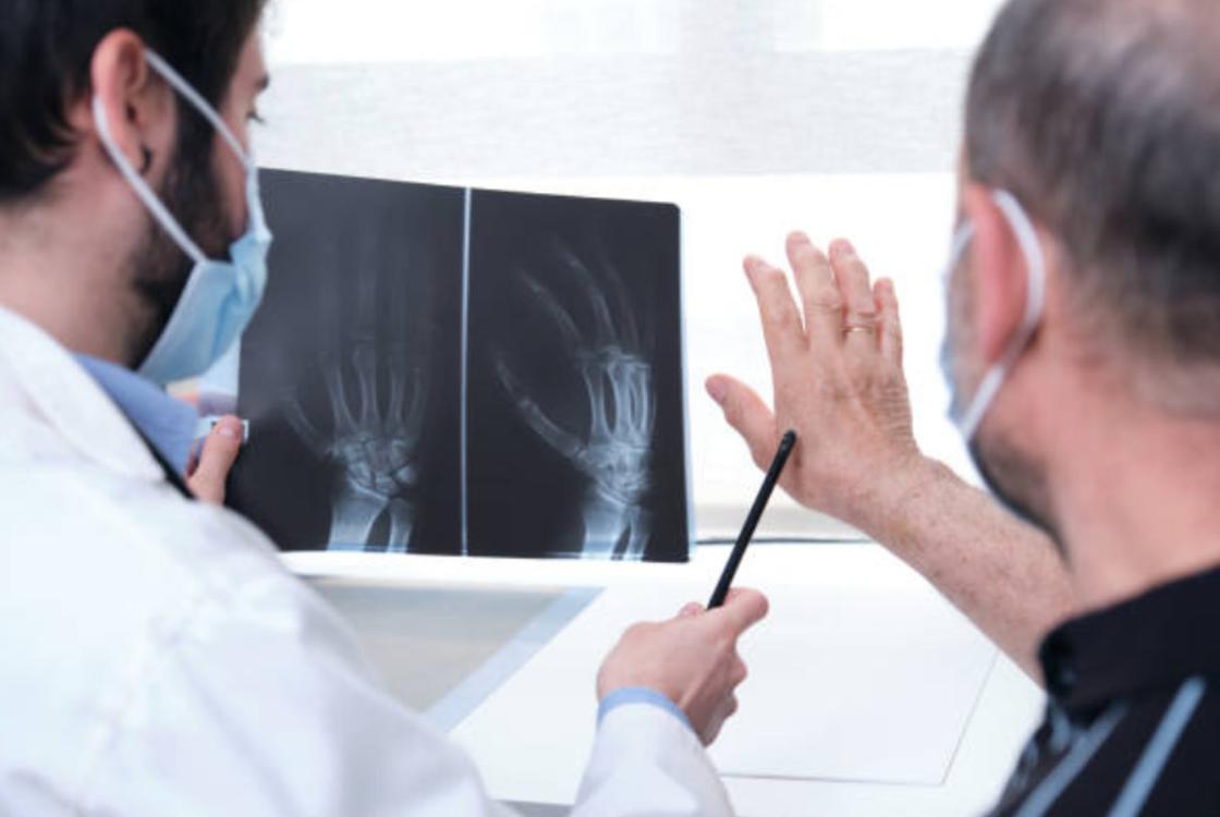 Врач объясняет пациенту показания рентгеновского снимка его кистей