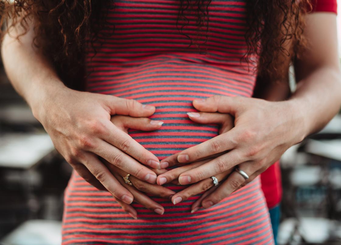Беременная женщина держит руки на животе