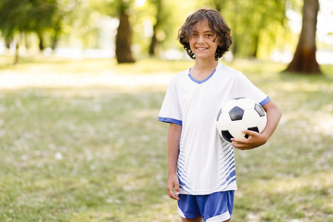 Мальчик в спортивной форме с мячом