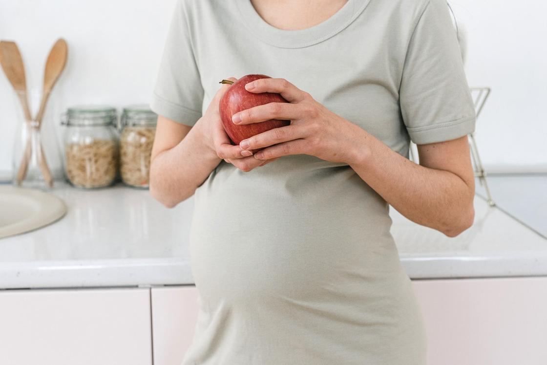 Беременная женщина с яблоком в руках