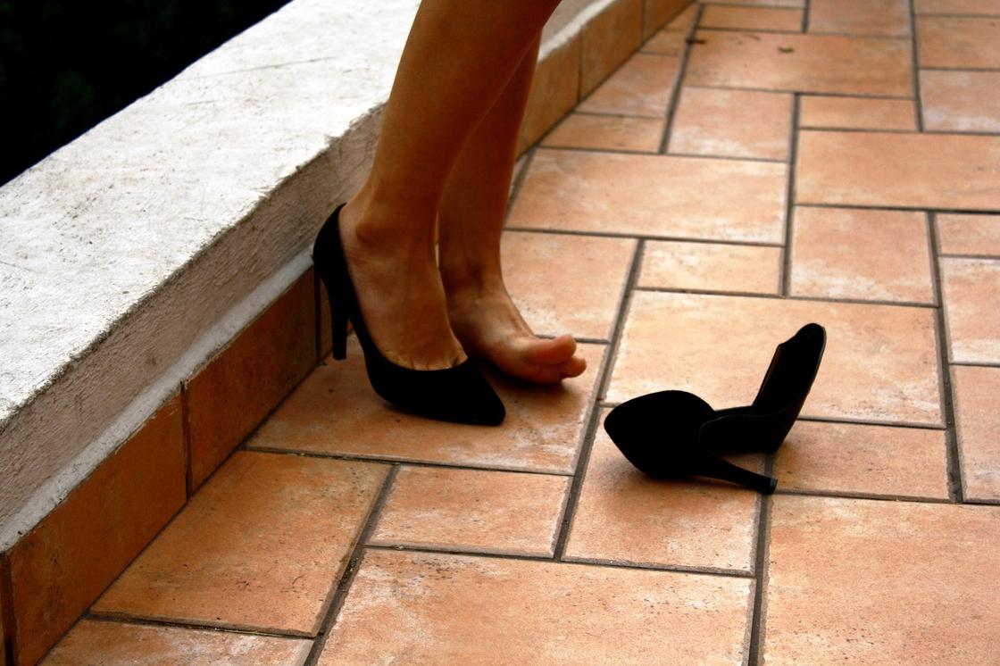Женщина снимает на улице туфли
