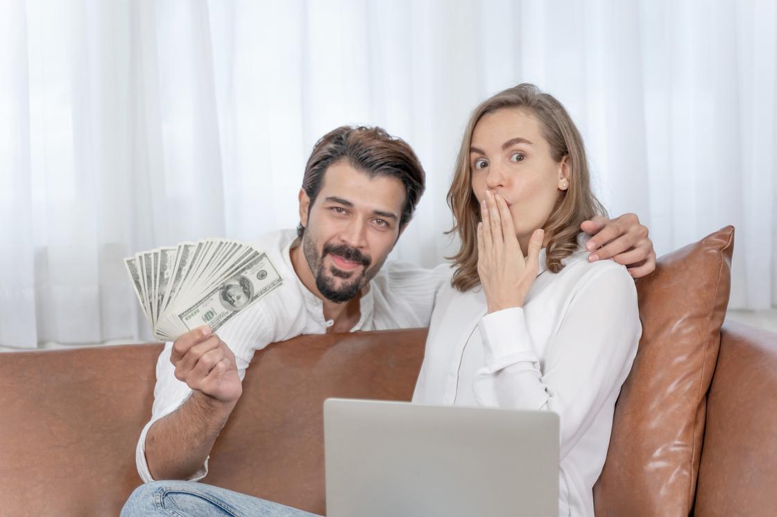 Мужчина и женщина с ноутбуком и деньгами в руках
